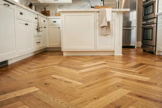 Parquet chêne en chevron dans une cuisine moderne avec îlot central et armoires blanches
