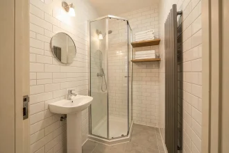Petite salle de bain de 3 m² optimisée avec douche à l'italienne, lavabo colonne et rangements muraux astucieux